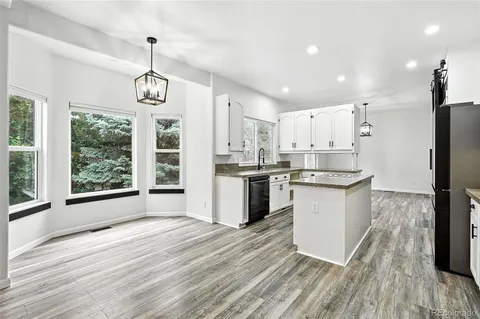 a kitchen with stainless steel appliances granite countertop a refrigerator a oven a stove and a wooden floors