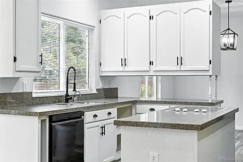 a kitchen with granite countertop a sink and white cabinets