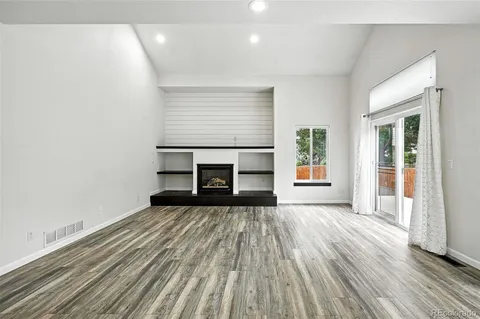 an empty room with windows and fireplace