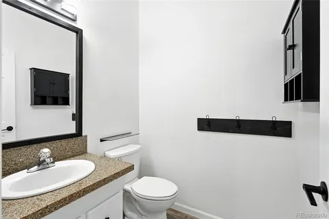 a bathroom with a granite countertop sink a toilet a mirror and shower