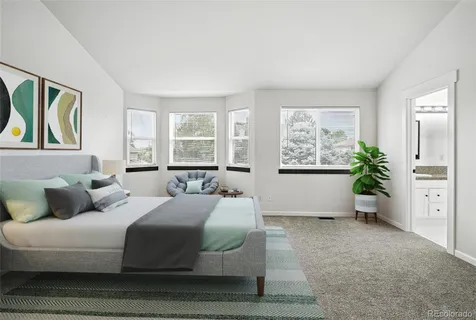 a bedroom with a large bed a potted plant and windows