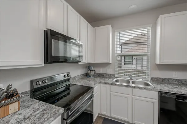 a kitchen with granite countertop a sink stove and cabinets
