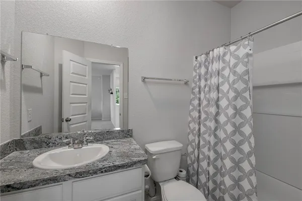 a bathroom with a granite countertop sink toilet and a mirror