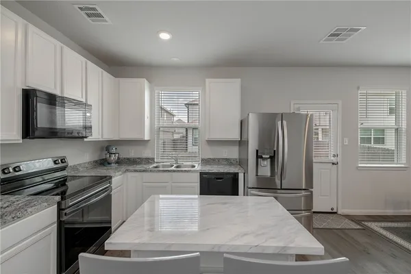 a kitchen with stainless steel appliances granite countertop a stove a refrigerator a sink a microwave and island
