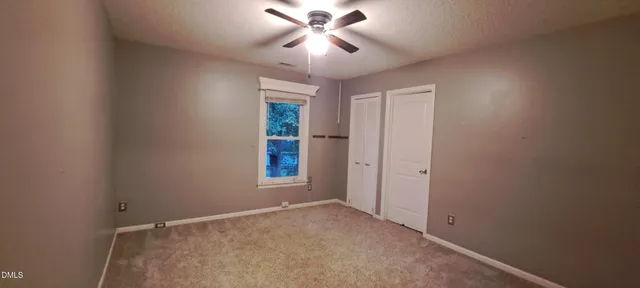 a view of empty room with window and chandelier fan