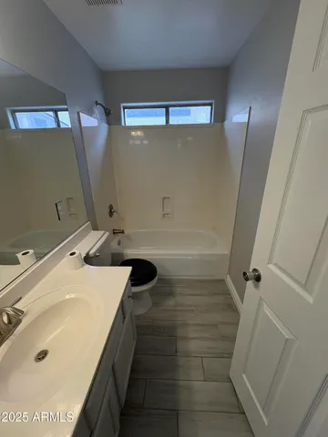 an empty room with wooden floor chandelier fan and windows