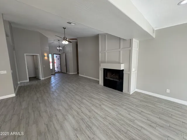 an empty room with wooden floor fireplace and hallway