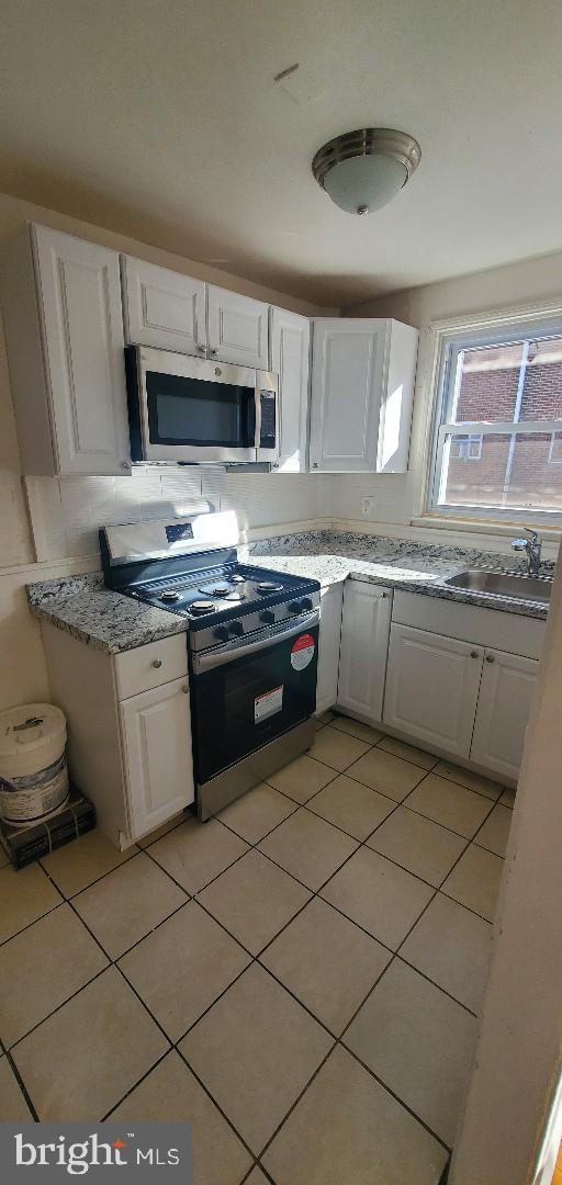 425 Glendale Road Upper Darby, PA 19082 - Photo 5 of 10 a kitchen with stainless steel appliances granite countertop a stove a sink and a microwave