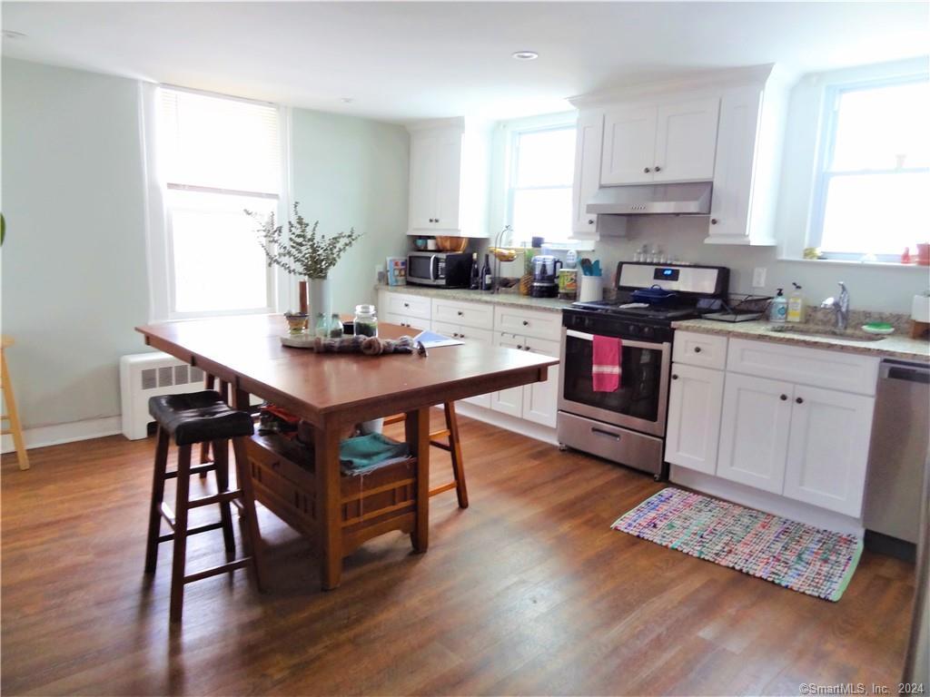 237 Brewster Street Bridgeport, CT 06605 - Photo 2 of 23 a kitchen with stainless steel appliances granite countertop a stove a sink dishwasher a microwave oven and a dining table with wooden floor