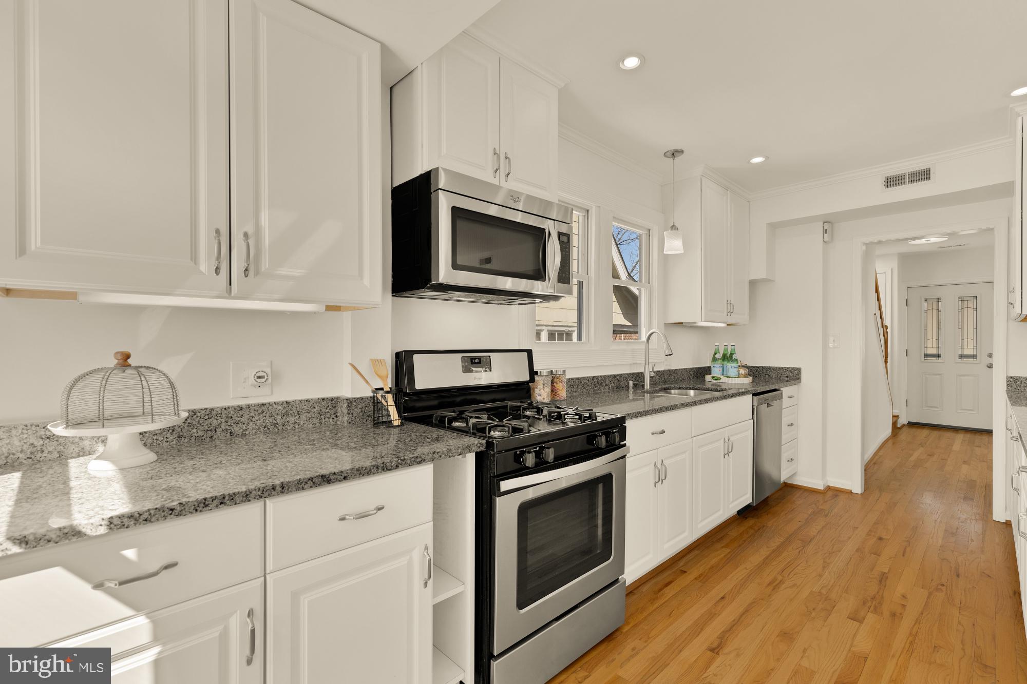2425 Perry Street Northeast Washington, DC 20018 - Photo 12 of 43 a kitchen with granite countertop a stove top oven a sink dishwasher and white cabinets with wooden floor
