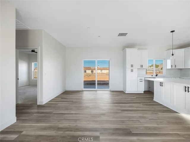 a view of an empty room with window and wooden floor