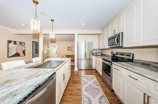 a large kitchen with granite countertop a stove and a sink
