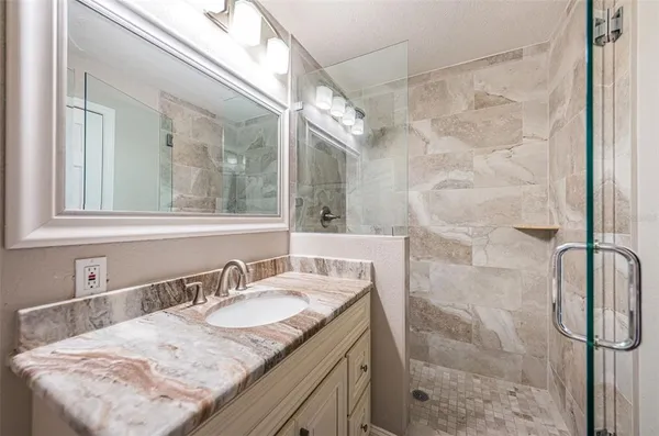 a bathroom with a granite countertop sink a mirror and shower