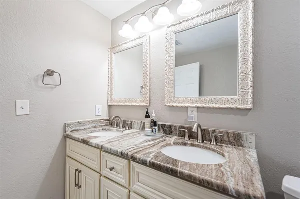 a bathroom with a granite countertop double vanity sink and a mirror