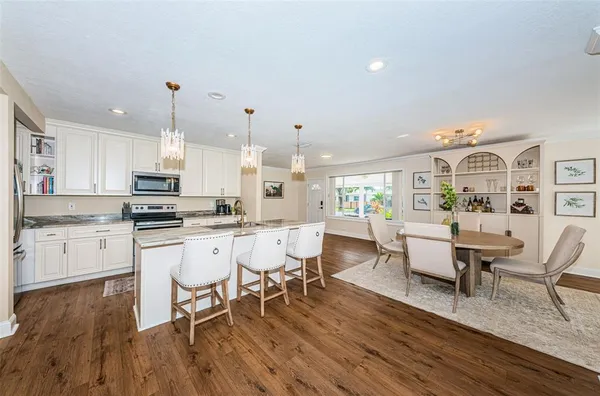 a living room with stainless steel appliances granite countertop furniture wooden floor and a kitchen view