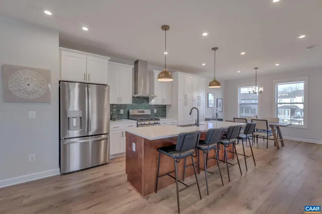 a kitchen with stainless steel appliances granite countertop a refrigerator a stove a sink a dining table and chairs