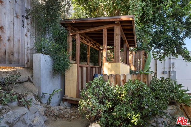 a view of a wooden house with a small yard and plants