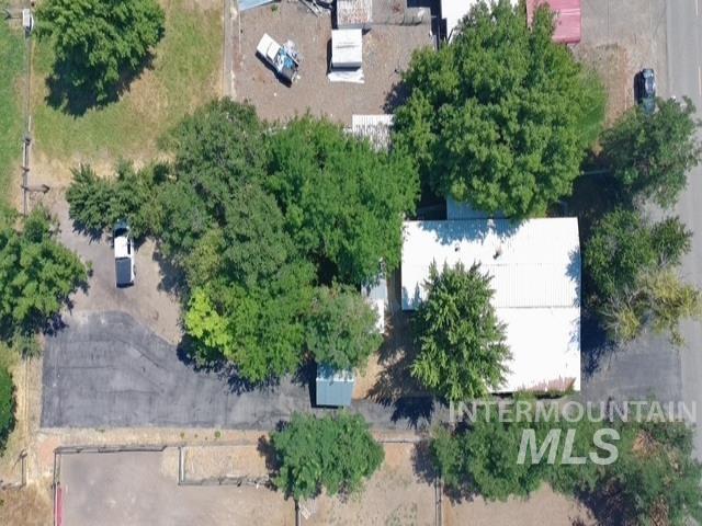 1360 Pioneer Road Weiser, ID 83672 - Photo 46 of 47 Property featuring a white corrugated metal roof, mature trees, and a paved parking area