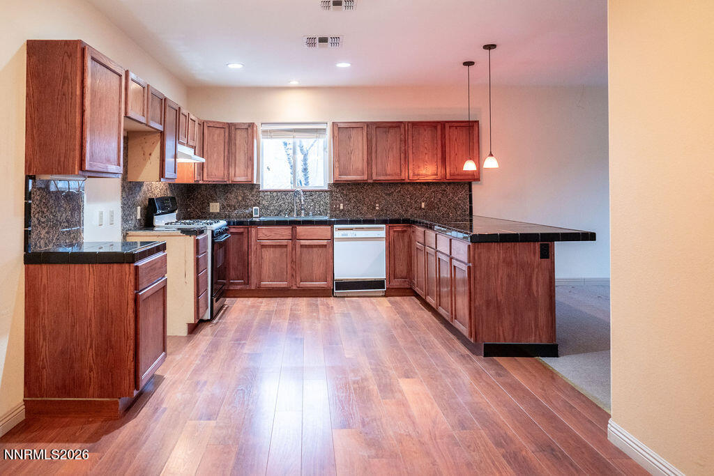 2931 Airport Road Carson City, NV 89706 - Photo 5 of 35 a kitchen with stainless steel appliances granite countertop wooden cabinets a stove top oven a sink and dishwasher