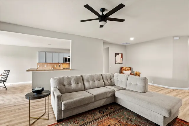 a kitchen with stainless steel appliances kitchen island granite countertop a sink a stove top oven a dining table and chairs with wooden floor