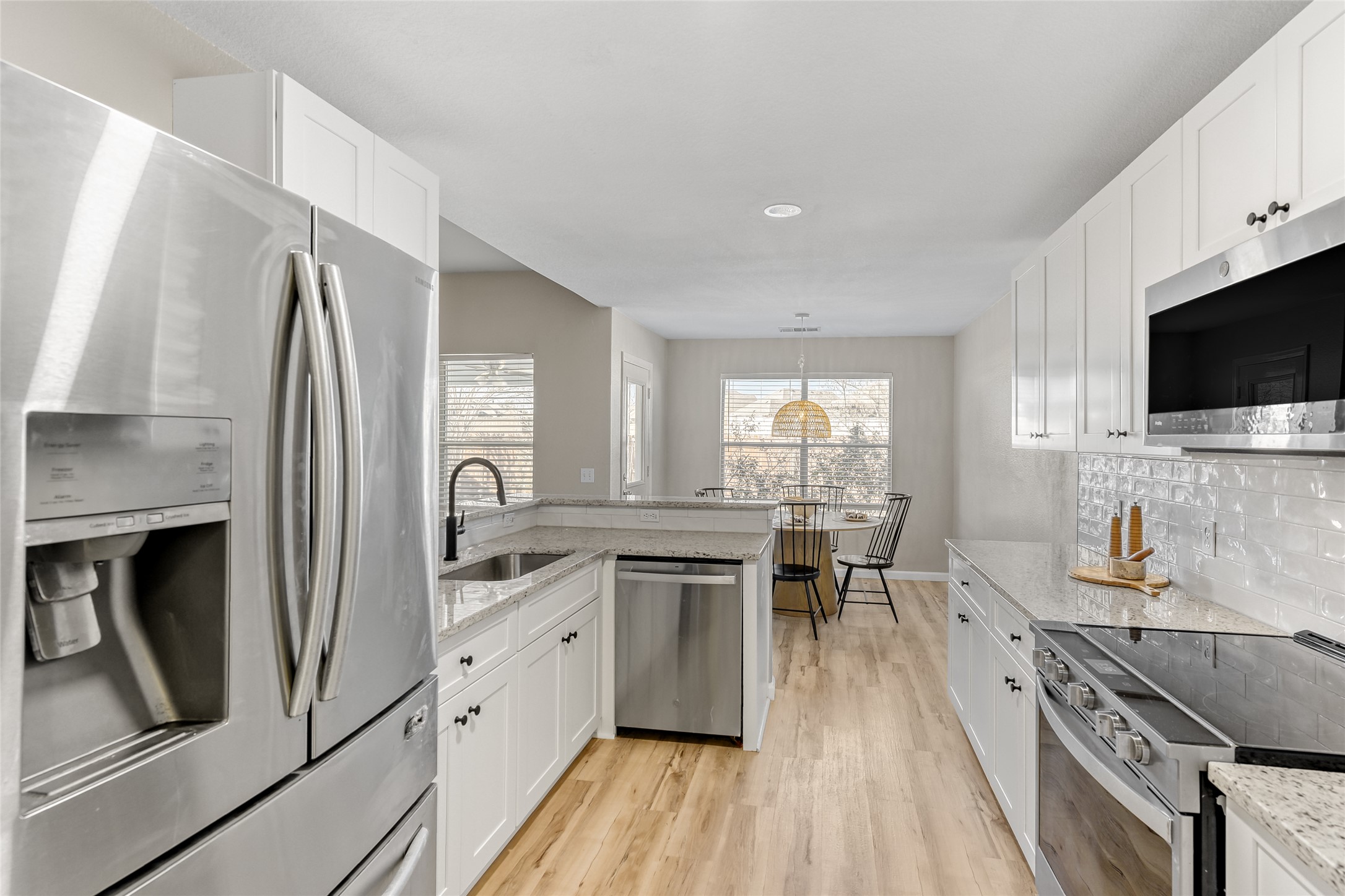 292 Spruce Drive Kyle, TX 78640 - Photo 13 of 25 a kitchen with stainless steel appliances granite countertop a stove top oven a sink a dining table and chairs with wooden floor