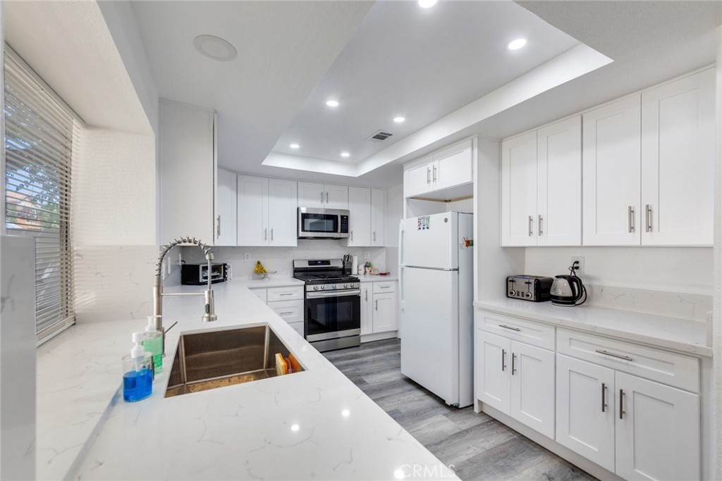 4179 Shellicia Circle Jurupa Valley, CA 92509 - Photo 8 of 25 a kitchen with stainless steel appliances a stove a sink a refrigerator a white cabinets and wooden floor