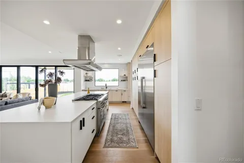 a large white kitchen with a sink and stainless steel appliances