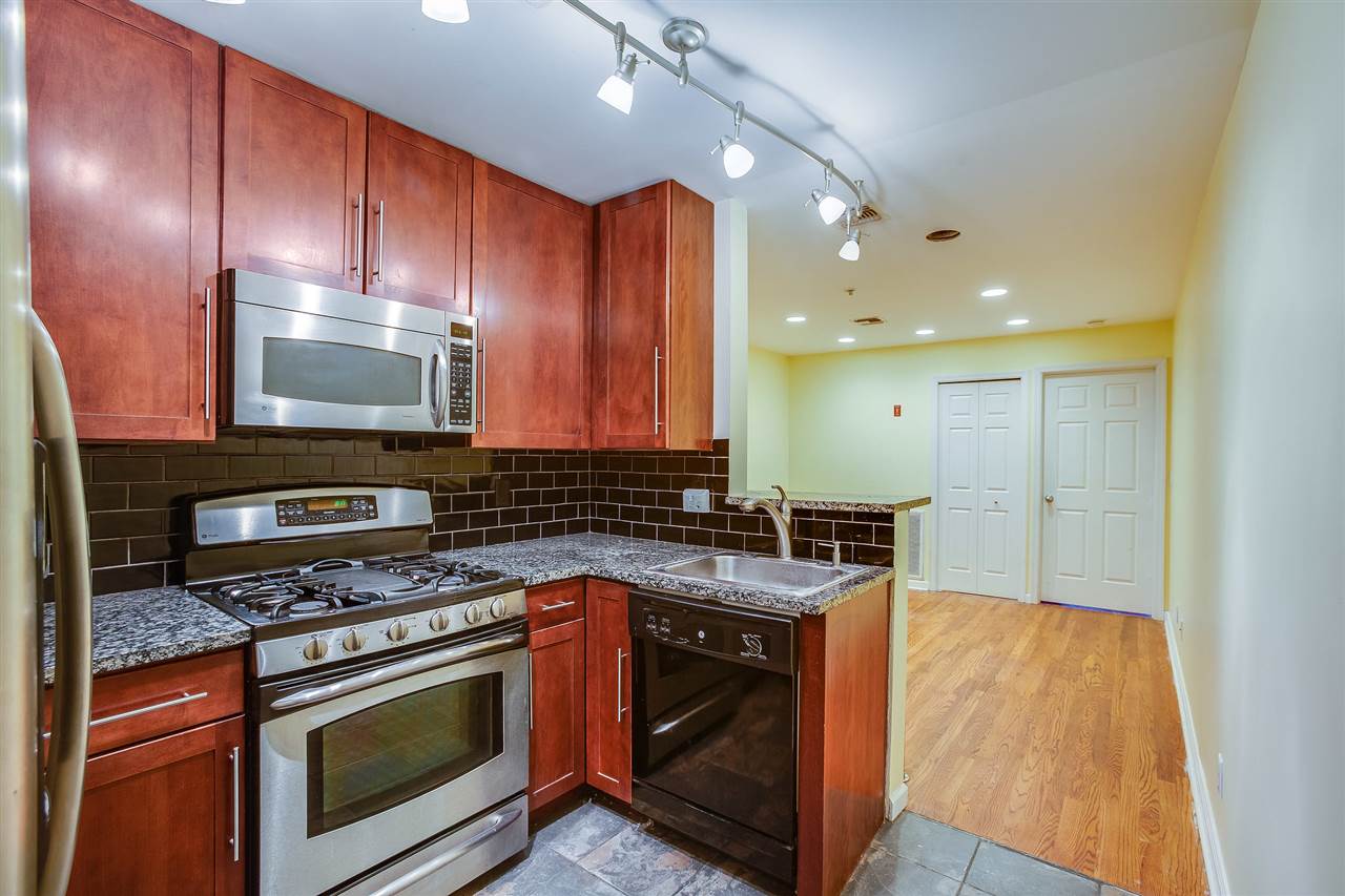 a kitchen with granite countertop wood cabinets stainless steel appliances and a sink