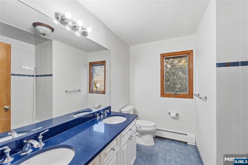 325 High Street Closter, NJ 07624 - Photo 16 of 34 a bathroom with a granite countertop double vanity sinks a mirror and a lamp