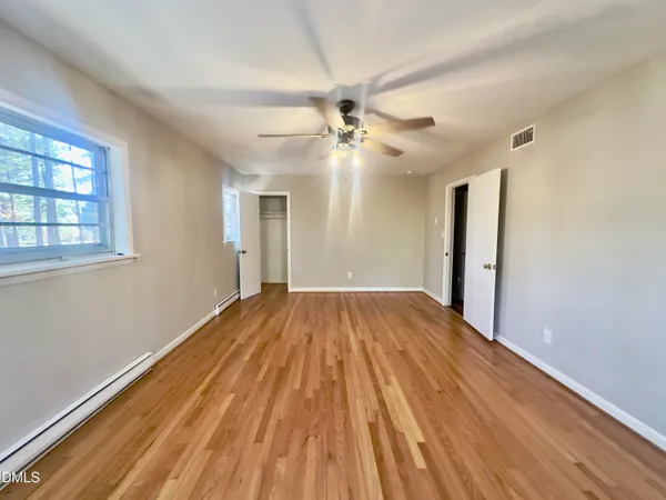 a view of empty room with wooden floor and fan