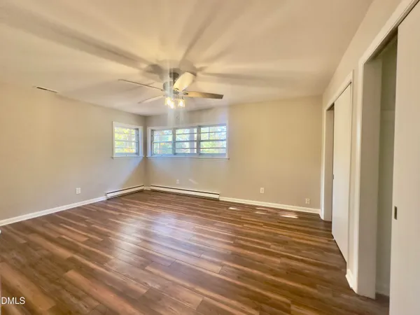 a view of an empty room with wooden floor and a window