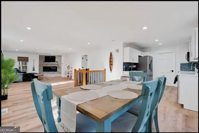 a kitchen with stainless steel appliances kitchen island granite countertop a dining table chairs and a refrigerator