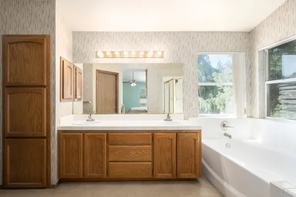 a spacious bathroom with a double vanity sink mirror and bathtub