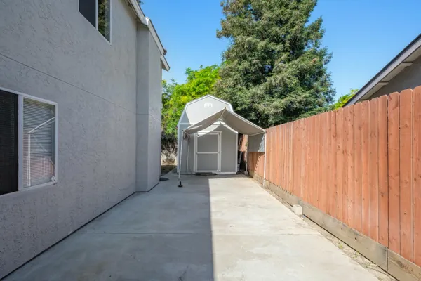 a view of a back yard with plants and wooden fence