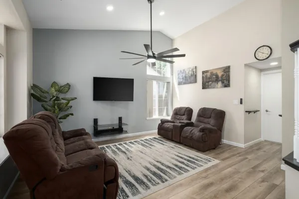 a living room with furniture a ceiling fan and a flat screen tv