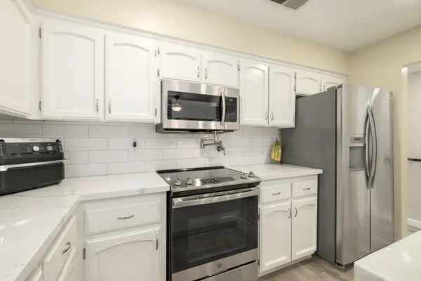 a kitchen with stainless steel appliances white cabinets white stove a microwave and a refrigerator