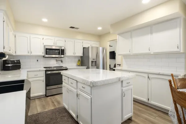 a kitchen with kitchen island granite countertop white cabinets stainless steel appliances and sink