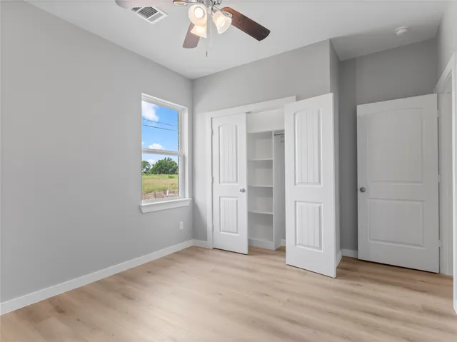 an empty room with wooden floor chandelier and windows