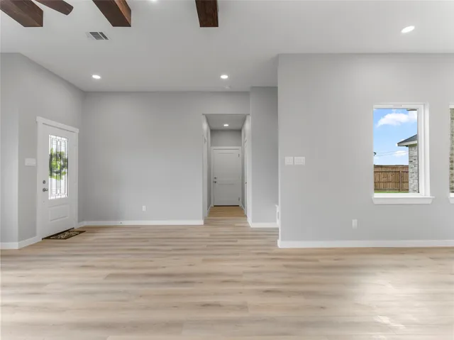 a view of an empty room with window and wooden floor