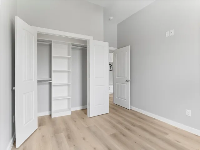 a view of an empty room with closet and wooden floor