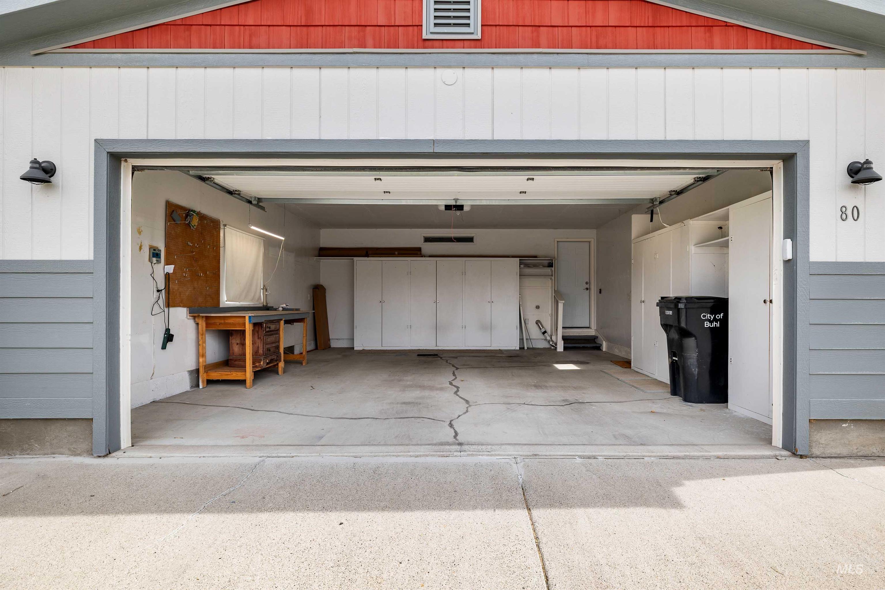 910 Moonglo, Unit 80 Buhl, ID 83316 - Photo 23 of 25 Two-car garage featuring built-in cabinetry, a rear entry door, and exterior wall sconces