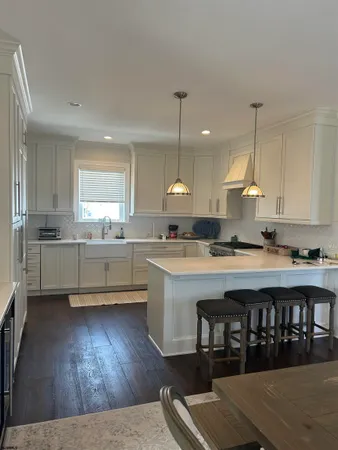 a kitchen with kitchen island granite countertop a sink cabinets and wooden floor