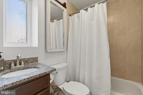 a bathroom with a granite countertop sink and a toilet