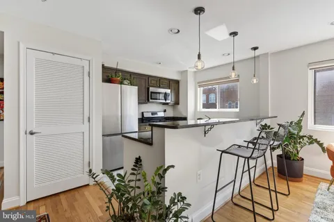 a kitchen with stainless steel appliances granite countertop a refrigerator a stove a microwave oven a sink with wooden floor and cabinets