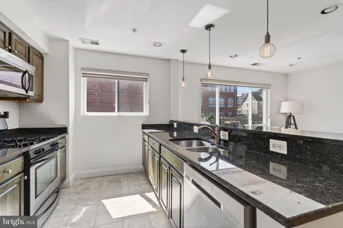 a kitchen with stainless steel appliances granite countertop a stove a sink and a microwave