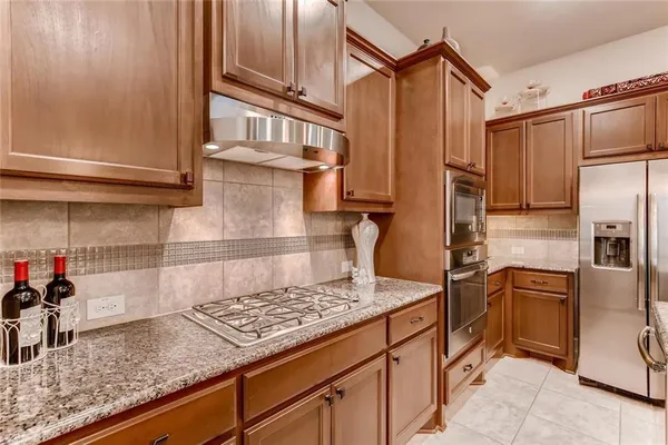 a kitchen with stainless steel appliances granite countertop a sink refrigerator and cabinets