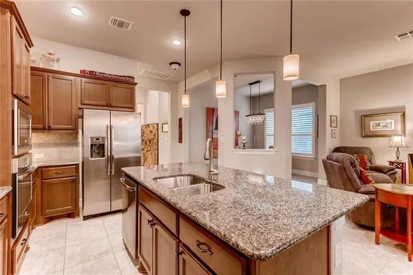 a kitchen with stainless steel appliances granite countertop a sink a stove and a wooden floor