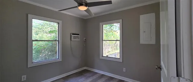 a view of an empty room with wooden floor and a window
