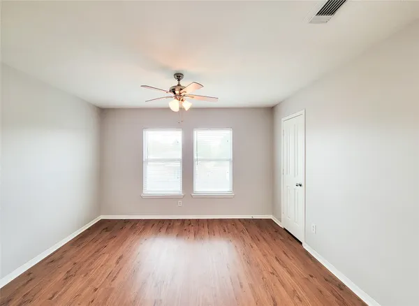 an empty room with wooden floor and windows