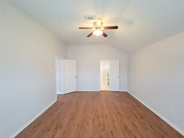a view of a room with wooden floor a ceiling fan and windows